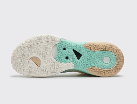 Bottom view of athletic shoe sole showing turquoise and tan textured pattern with circular and geometric details