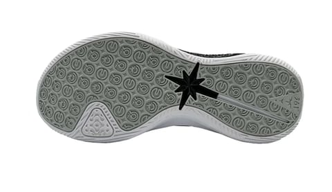 Bottom view of a gray athletic shoe sole with tread pattern and black star marking